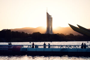 Visitatori sul ponte galleggiante al tramonto, con il Millennium Tower oltre Copa Beach.