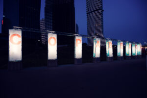 Colonne luminose con le lettere di Copa Beach davanti ai grattacieli di Donau City, all'imbrunire.