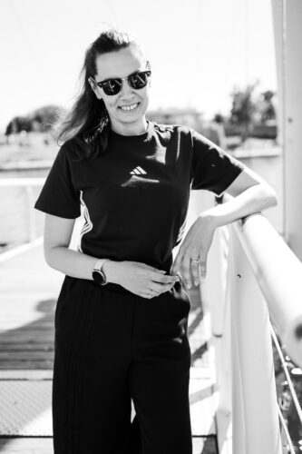 Ritratto in bianco e nero di Adriana, sorridente con occhiali da sole, sul molo di Copa Beach.