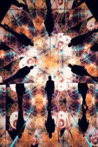 Adriana steht im Pyramidenraum mit warmen orangefarbenen Kaleidoskop-Projektionen und kreisförmigen Symbolen.