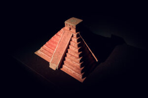 Maßstabsmodell einer Maya-Stufenpyramide, von oben beleuchtet in einem dunklen Ausstellungsraum.