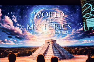 Große Projektionsleinwand mit der Titelkarte von World of Mysteries, einer Maya-Pyramide und Sternenhimmel.