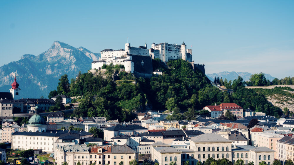 Fortezza di Hohensalzburg sulla collina sopra il centro storico di Salisburgo, con il fiume Salzach in primo piano.